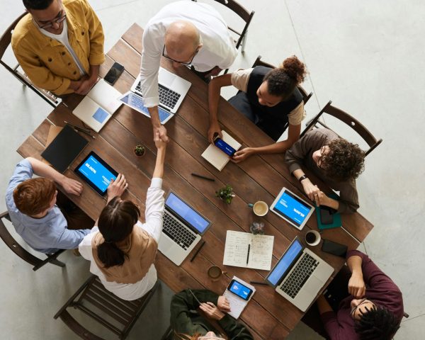 Top view of a diverse team collaborating in an office setting with laptops and tablets, promoting cooperation.