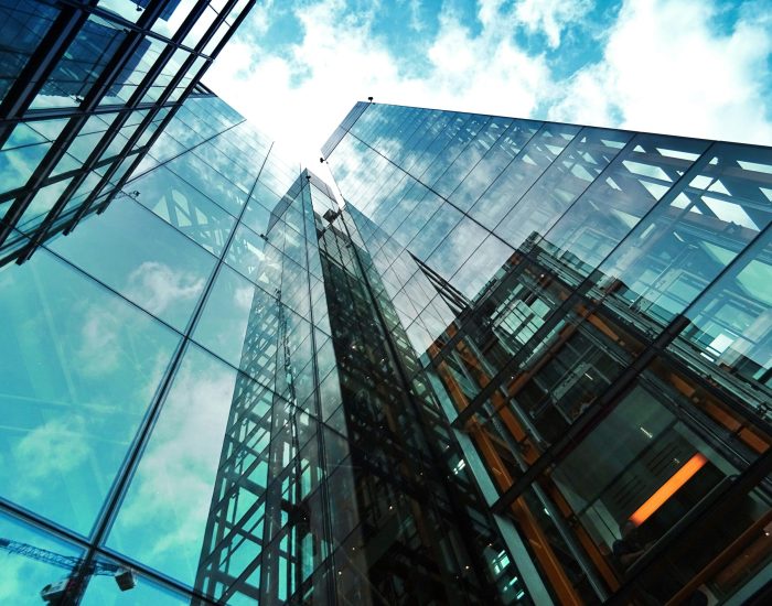 A striking view of a modern glass skyscraper reflecting the sky and clouds.