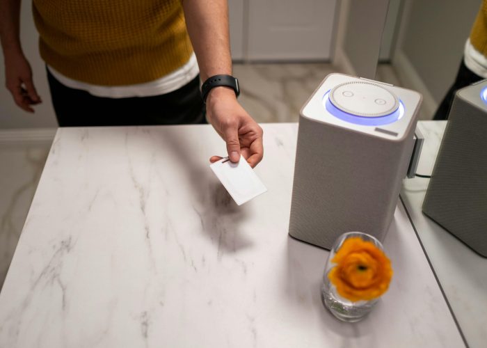 A person interacts with a smart speaker on a marble table, showcasing contemporary technology use.